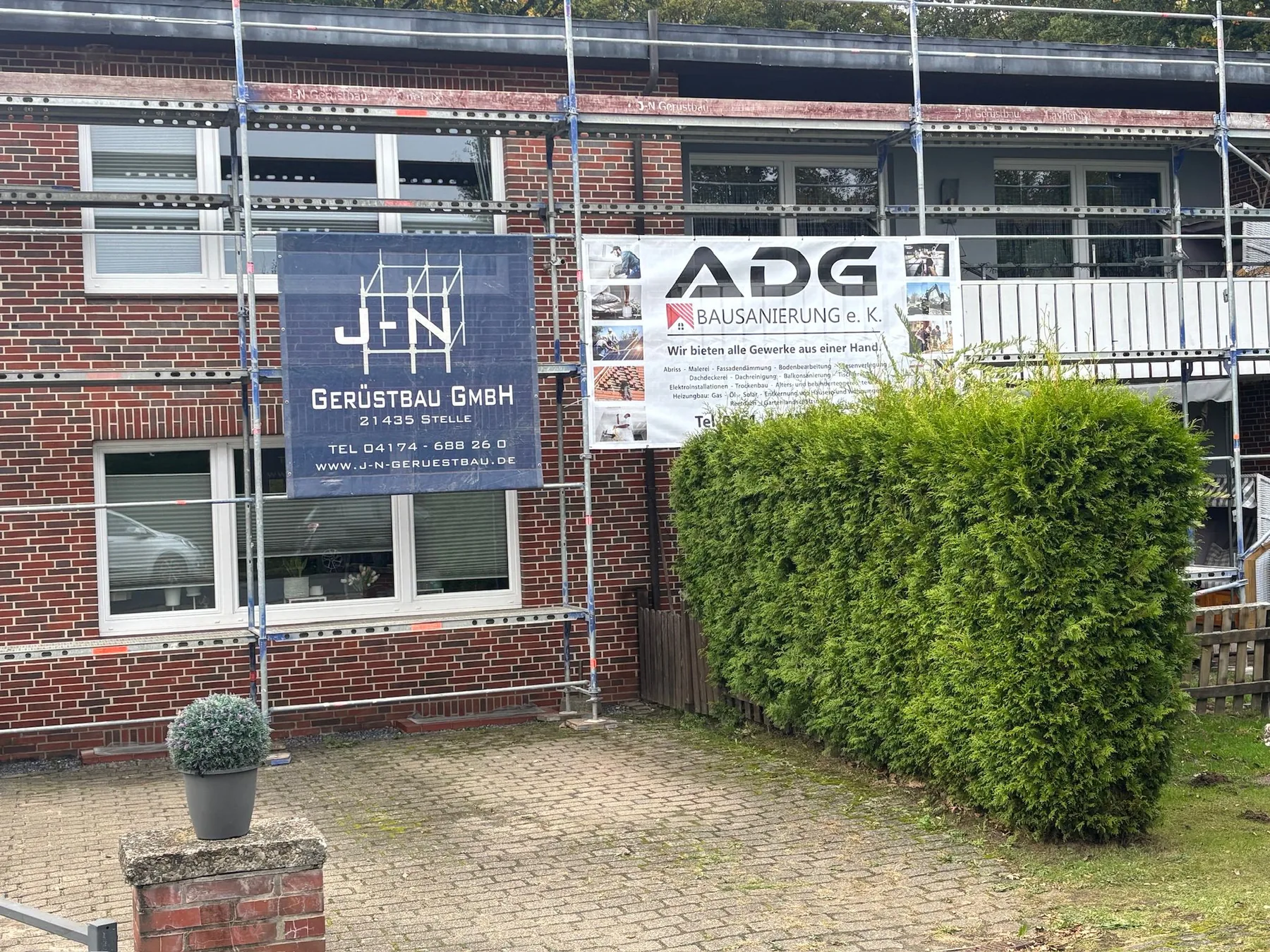 Sanierungsarbeiten an einer eingerüsteten Fassade mit ADG Bausanierung Banner
